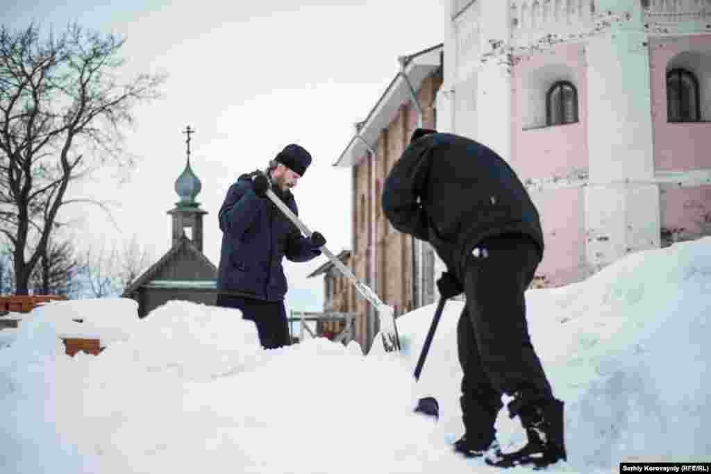 Настоятель монастыря Дионисий и прихожинин Кирилл убирают снег. Иногда Кирилл живет в монастыре неделями, участвует в религиозных церемониях и помогает с ежедневными делами