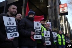 Câțiva muncitori din domeniul feroviar participă la o grevă în fața gării Euston din Londra, miercuri, 1 februarie 2023.