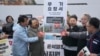 Protesters wearing masks of Ukrainian President Volodymyr Zelenskiy and South Korean President Yoon Suk Yeol hold a banner at a rally against their government's plans to supply weapons to Ukraine in Seoul on November 26.