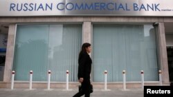 A woman walks past a closed branch of the Russian Commercial Bank in Nicosia, Cyprus. Natalya Orlova says Cyprus's liquidity crisis will become clear when the banks reopen.