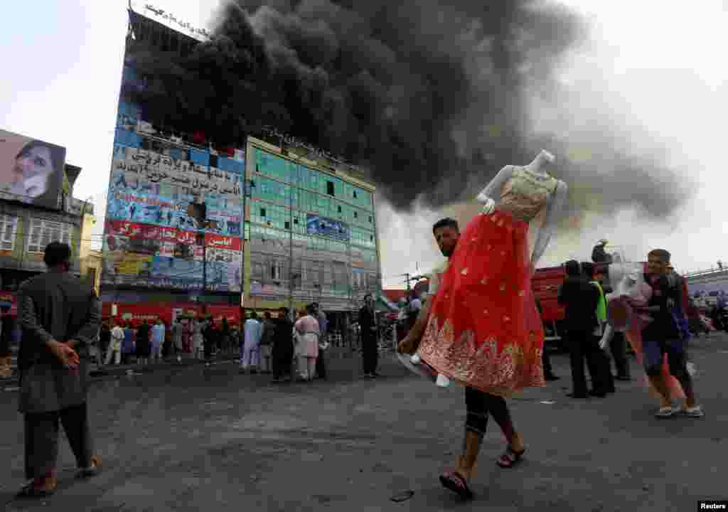 An Afghan shopkeeper carries a mannequin after a fire broke out at a shopping mall in Kabul. (Reuters/Omar Sobhani)