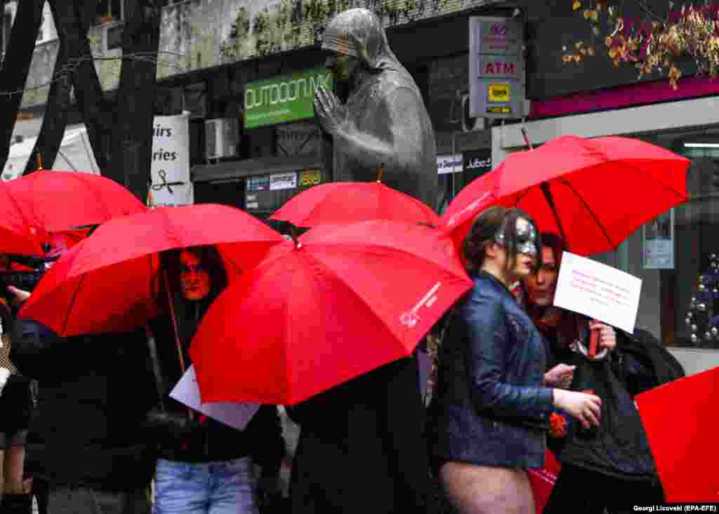 Macedonian sex workers carry red umbrellas around the monument of Mother Theresa before a rally to mark the International Day to End Violence Against Sex Workers in Skopje, Macedonia. (epa-EFE/Georgi Licovski)