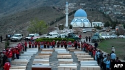 د افغانستان د سرې میاشتې ټولنې غړي پر روغتون د پاکستان په برید کې د وژل شویو له تابوتونو سره ولاړ دي - د مارچ ۱۸مې انځور.