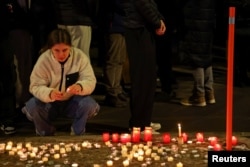 Жена държи свещ пред бара „Le Constellation“