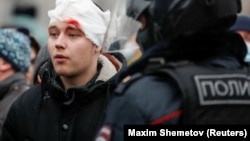 An injured protester looks on as riot police disperse anti-government protests in Moscow on January 23.