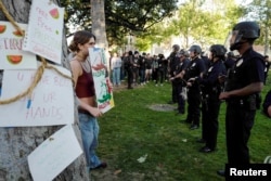 Scene de la Universitatea din Sudul Californiei (USC): o tânără ține un semn prin care cere libertate pentru Palestina în fața poliției din Los Angeles.