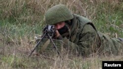 Ілюстрацыйнае фота. Вайсковец без апазнавальных знакаў цэліцца ва ўкраінскіх вайскоўцаў, Бельбек, 4 сакавіка 