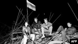 Young people sit on a barricade in front of the Russian White House in central Moscow on August 20 1991, during the abortive coup.