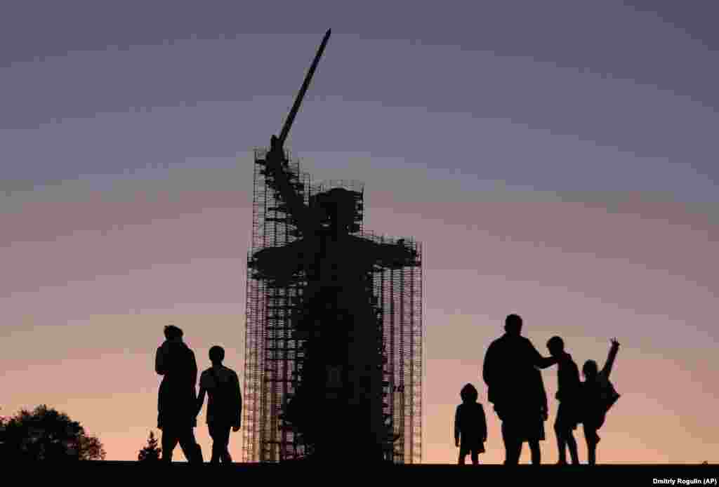 People walk near the statue The Motherland Calls under reconstruction in Mamayev Kurgan, the main site of the Battle of Stalingrad memorial, during sunset in Volgograd. (AP/Dmitry Rogulin)