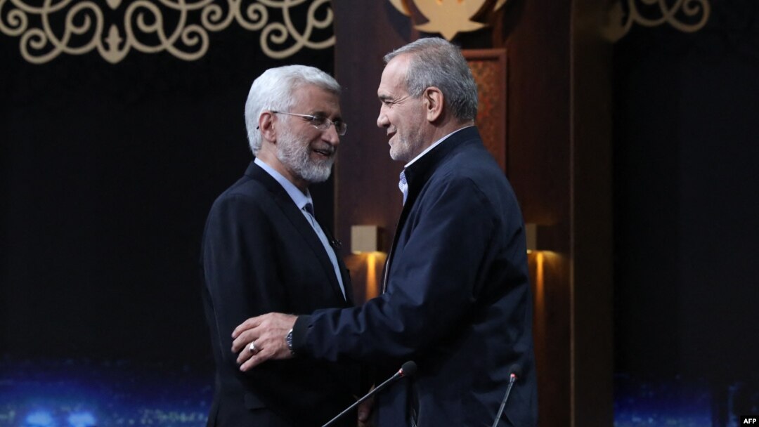 Candidatul Saeed Jalili (left), de linie dură, îi strânge mâna candidatului reformist Masud Pezeshkian, după o dezbatere televizată din 1 iulie. 