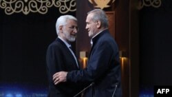 Candidatul Saeed Jalili (left), de linie dură, îi strânge mâna candidatului reformist Masud Pezeshkian, după o dezbatere televizată din 1 iulie. 