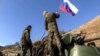 Two soldiers attaching a flag on the Russian peacekeeping forces' military vehicle as they move on the road towards Martuni in Nagorno-Karabakh. November 13, 2020.