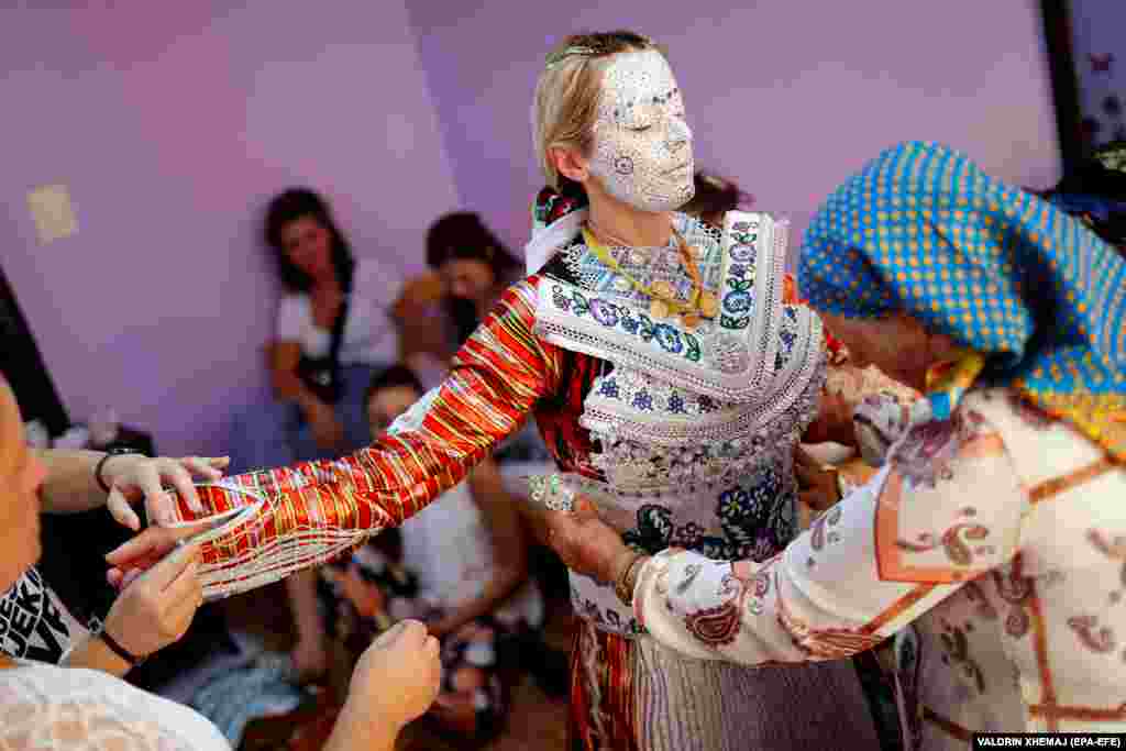 Women from the village dress the bride up for her big day.