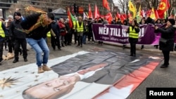 A protester jumps on a poster of Turkish President Recep Tayyip Erdogan at a demonstration against Sweden's NATO bid arranged by the Kurdish Democratic Society Center in Stockholm on January 21.