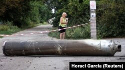 Жінка дивиться на частину ракети після російського військового удару. Краматорськ, Донецька область, Україна, 11 серпня 2022 року