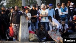 Macedonia -- People, part of a new group of more than a thousand immigrants, gather near a Yugoslavia border stone, as they wait at the border line of Macedonia and Greece to enter into Macedonia near Gevgelija railway station, August 20, 2015