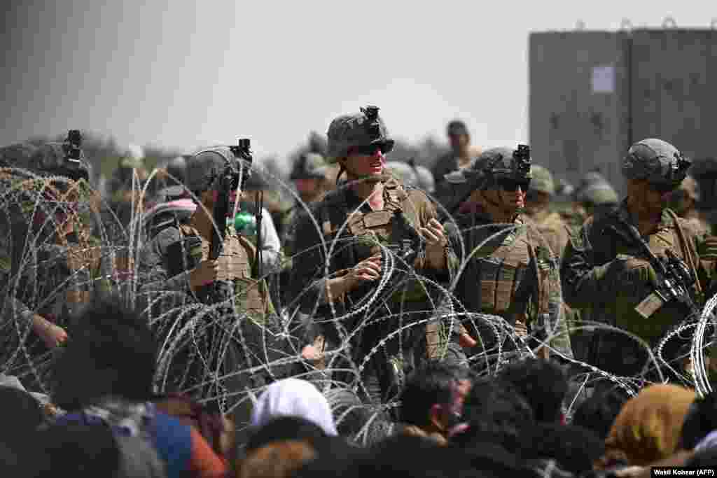 Soldați americani stau de pază în spatele sârmei ghimpate, lângă zona militară a aeroportului din Kabul, 20 august 2021. &nbsp;