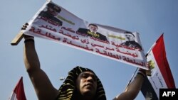 A man, dressed up as an Egyptian pharaoh, holds a banner bearing a portrait of Egyptian President Muhammad Morsi flanked by portraits of Italian dictator Benito Mussolini and German Nazi leader Adolf Hitler on Cairo's landmark Tahrir Square on November 30.