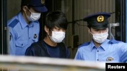 Тэцуя Ямагамиді (ортада) айдауылдар әкетіп бара жатыр.