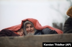 Две беженки накрываются одеялом, выезжая из чеченского села Катыр-Юрт на кузове грузовика, 30 января 1995 года