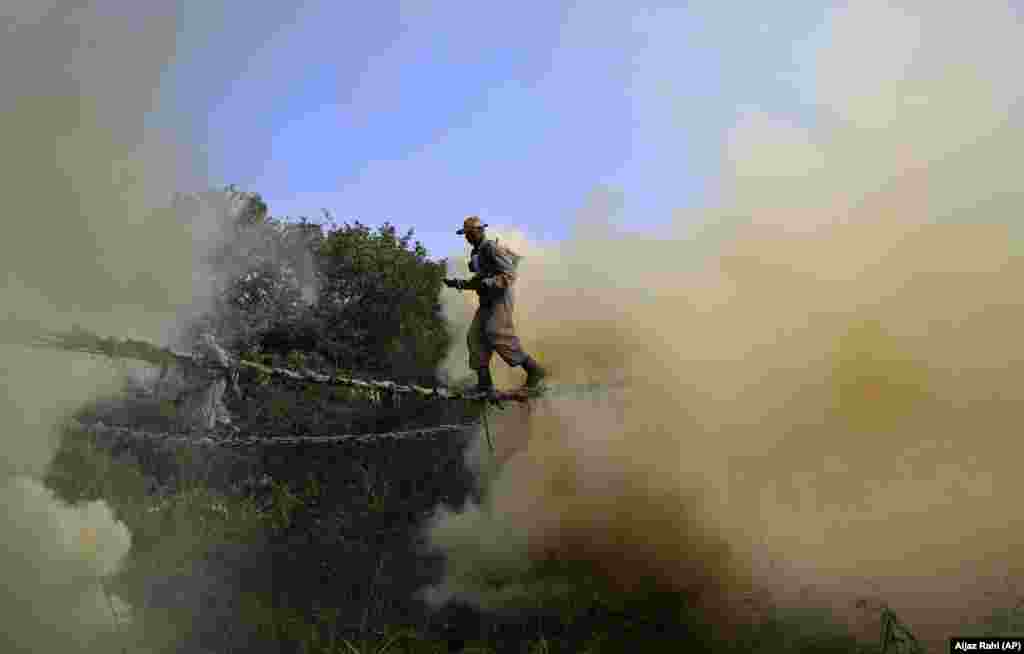 Indian Army soldiers cross a rope bridge amid smoke from canisters as they showcase their skills during a training session in Bangalore. (AP/Aijaz Rahi)