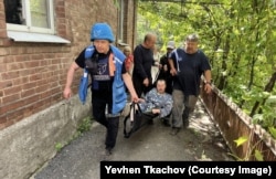Yevhen Tkachov (left) evacuates a man from his home in Kostyantynivka in June 2025.