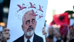 Një protestues duke mbajtur një pllakat me një karikaturë të kryeministrit të Shqipërisë, Edi Rama, gjatë një proteste në Tiranë, më 5 qershor 2026, kundër një projekti luksoz turistik në bregdetin e Adriatikut. 