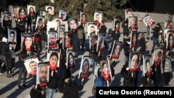 People hold placards with photos of the victims of Ukraine International Airlines flight PS752, which was shot down near Tehran by Iran's Revolutionary Guards, as they gather to take part in a march to mark its first anniversary, in Toronto on January 8, 2021.