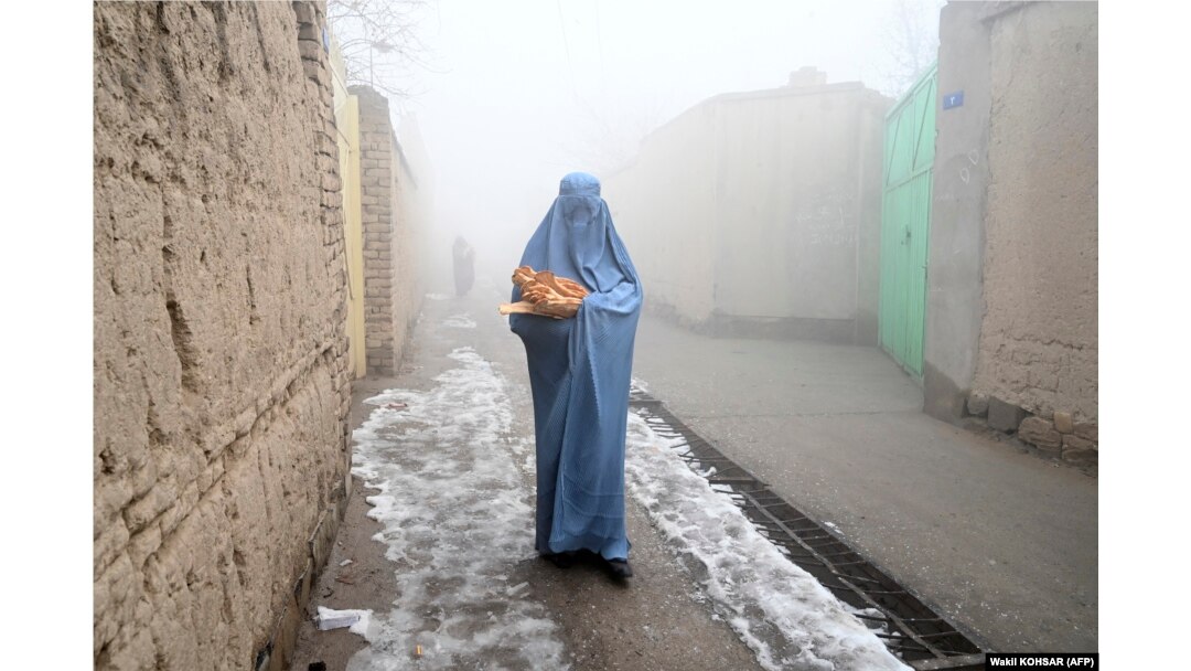 A woman wearing a burqa walks home after receiving free bread distributed as part of the Save Afghans From Hunger campaign in Kabul on January 18.