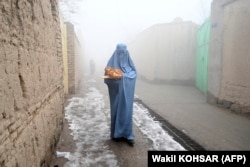 A woman wearing a burqa walks home after receiving free bread distributed as part of the Save Afghans From Hunger campaign in Kabul on January 18.