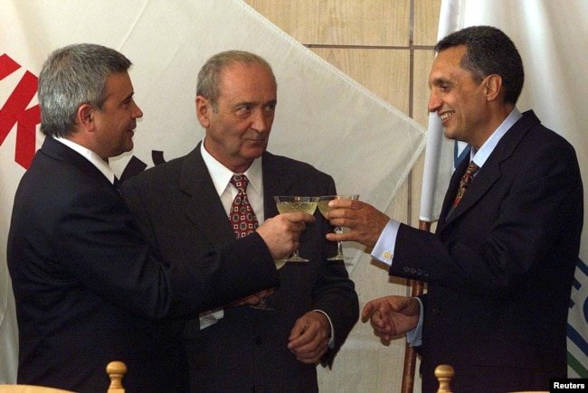 Kryeministri i atëhershëm bullgar, Ivan Kostov (në anën e djathë), duke pirë shampanjë së bashku me presidentin e LUKoil, Vagit Alekperov (në anën e majtë). Në prani të tyre gjendej edhe ambasadori i atëhershëm rus në Bullgari, Leonid Kerestidyan. Kjo fotografi është realizuar pas nënshkrimit të marrëveshjes së privatizimit të Burgas në tetor të vitit 1999.
