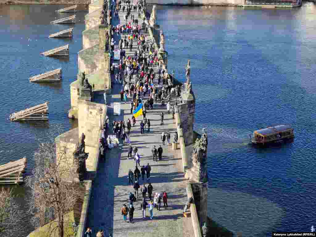 Люди на Карловому мосту у Празі, дехто вже з прапорами