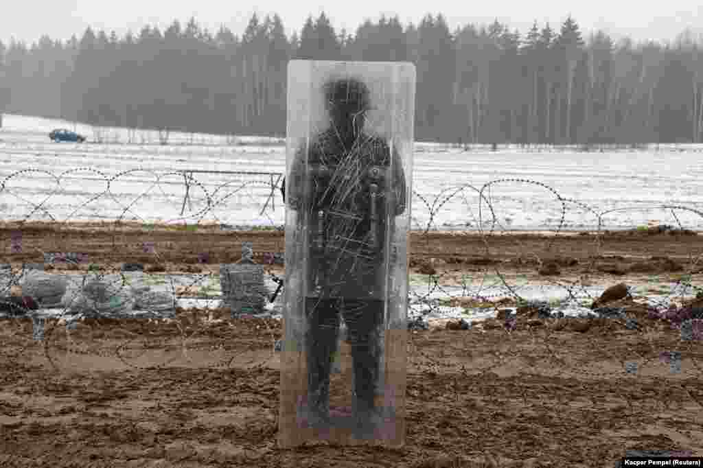 A Polish soldier stands behind a clear shield at the border construction site on January 27. A border guard spokeswoman told local media that the &quot;intention is for the damage to be as small as possible&quot; and noted that the wall was being erected along the same areas where temporary razor wire is already in place.