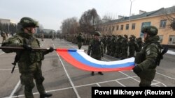 Российские военные складывают флаг во время церемонии начала вывода войск ОДКБ из Казахстана.