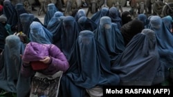 Afghan women wearing burqas wait for free bread in front of a bakery in Kabul in January.