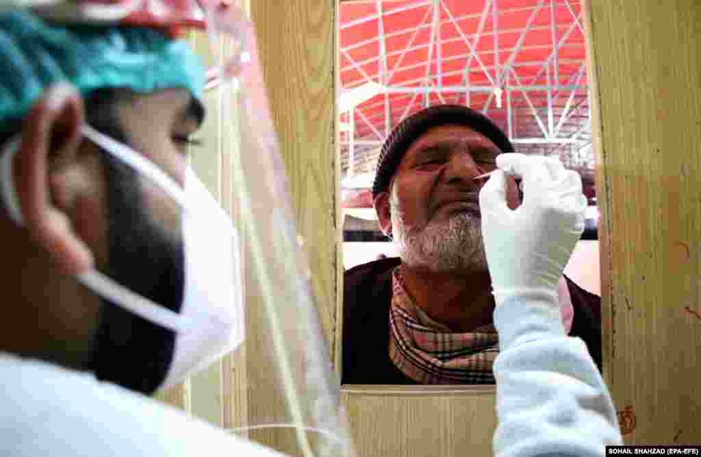 A Pakistani health worker takes a sample to test for COVID-19 during a surge in cases of the omicron variant in Islamabad.