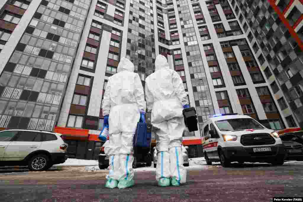 Doi medici îmbrăcați în combinezoane se deplasează la locuința unei persoane suspecte de Covid în Sankt Petersburg, Rusia, 24 ianuarie 2022.&nbsp;