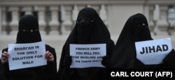 سه زن برقع‌پوش پلاکاردهایی را علیه اقدام نظامی فرانسه در مالی در دست دارند/ لندن، مقابل سفارت فرانسه، ژانویه ۲۰۱۳