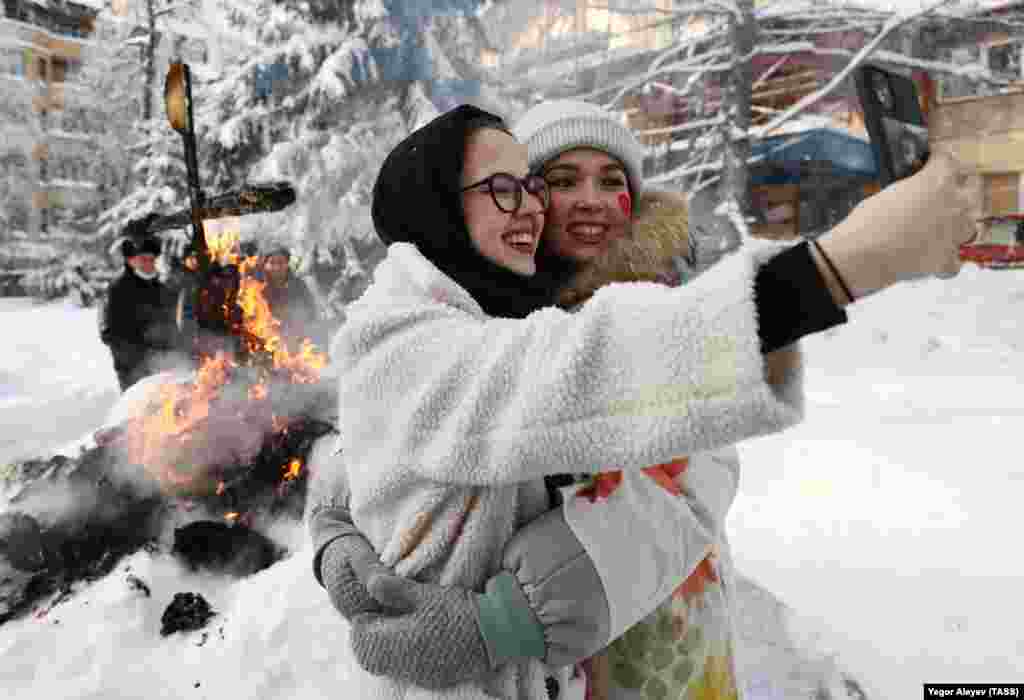 Două femei își fac un selfie în fața unei efigii ce simbolizează examenele studențești, cu ocazia Zilei Studenților Ruși din Kazan, 25 ianuarie 2022.
