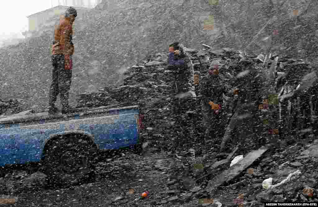 Afghan migrants work on a snowy day in the Iranian city of Meygun, north of Tehran.&nbsp;