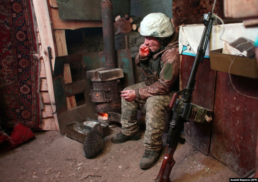 Një ushtar ukrainas duke tymosur një cigare në një strehim, pranë mitralozit të tij, në një pozicion në rajonin e Luhanskut, në lindje të Ukrainës, më 22 janar.