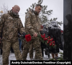 Украинские военнослужащие возлагают цветы к мемориалу жертвам ракетного обстрела, в результате которого семь лет назад в Мариуполе погиб 31 человек