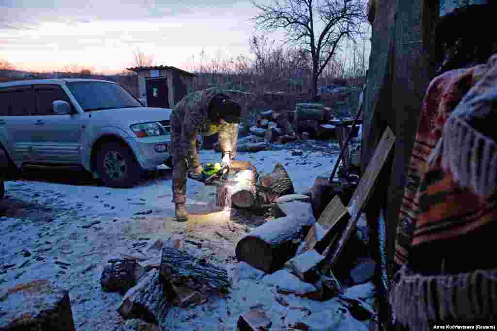 Украинский военнослужащий рубит дрова на передовой возле села Новомихайловка в Донецкой области, 21 января 2022 года