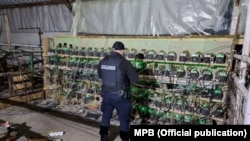 A Kosovar police officer surveys cryptocurrency mining equipment during a raid in Leposavic.