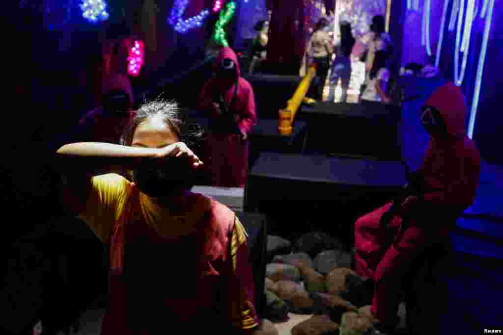 A customer plays &#39;Red Light, Green Light&#39; game from the Netflix show &#39;Squid Game&#39; at Strawberry Cafe in Jakarta, Indonesia, October 15, 2021