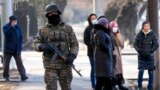 A Kazakh soldier patrols a street as relatives of the arrested in the anti-government protests gather near a police station in Almaty.