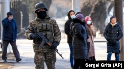 A Kazakh soldier patrols a street as relatives of arrested anti-government protesters gather near a police station in Almaty on January 14.