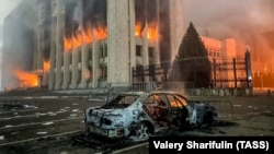 Сгоревший автомобиль возле охваченного огнем акимата Алматы, который подожгли в дни протестов, вылившихся в кровопролитие 
