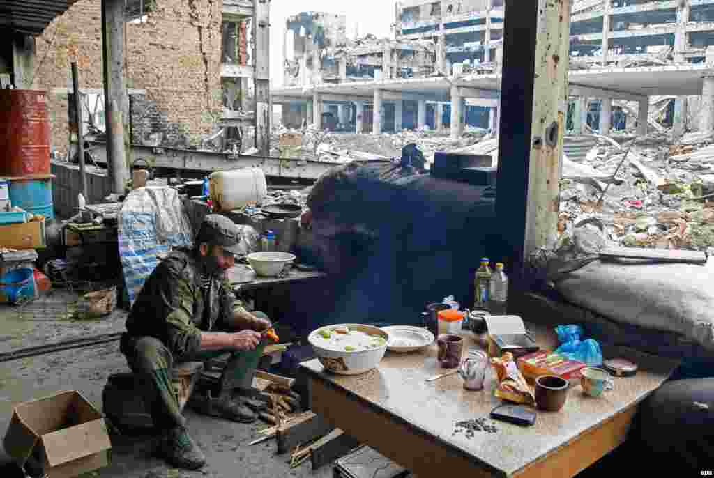 A pro-Russia separatist cooks food at the destroyed International Airport building in Donetsk, Ukraine. (epa/Alexander Ermochenko)