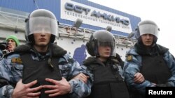 Riot police guard the Ostankino television tower in Moscow during a protest over the NTV program that alleged anti-Putin protesters were paid to attend demonstrations.